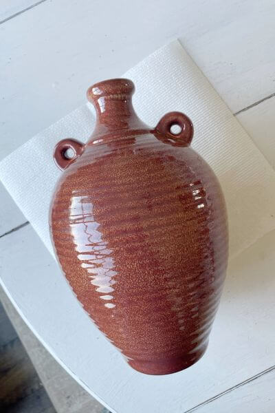 Brown and shiny ceramic vase laying on a paper towel.