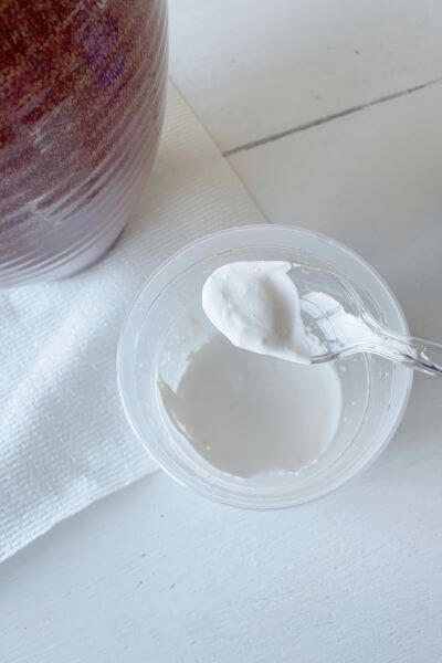 Mixture of white paint and baking soda in a small cup. 