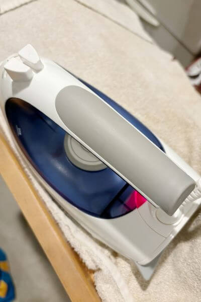 Iron placed over wet towel to soften glue that holds the veneer onto the wood. 