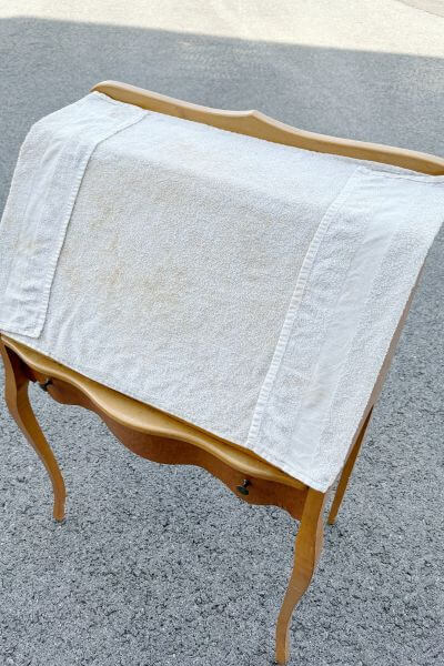 Wet towel over the part of the desk where the veneer needs to be removed. 