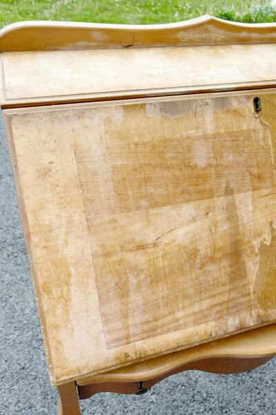 Veneer removed from front of desk but remnants of glue still apparent.
