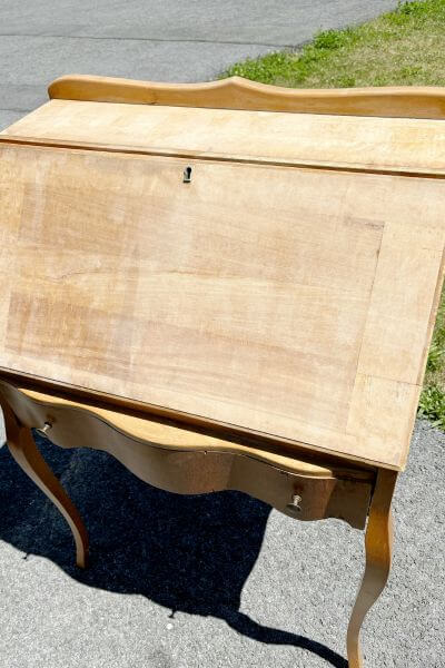Half the front of the desk sanded and the other half with glue still adhered. 