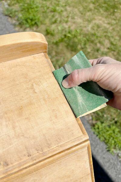 Sanding the hard-to-reach edges with a folded piece of sandpaper.