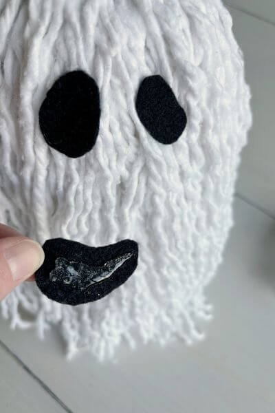 Hot glue felt eyes and mouth onto the mop head.