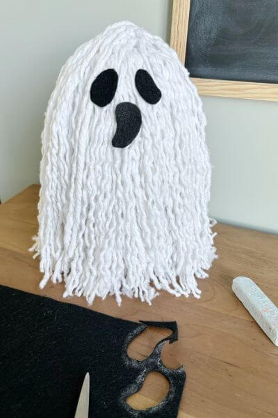 Completed mop head ghost DIY with felt eyes and mouth.