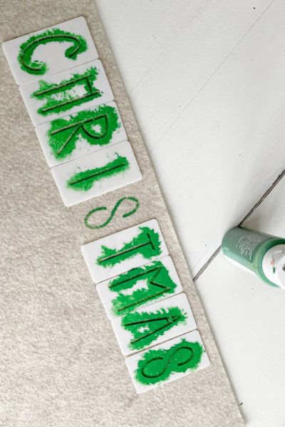 "Christmas" stenciled onto the felt using green paint. 