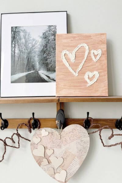 Spackle painting of three hearts displayed on a shelf. 