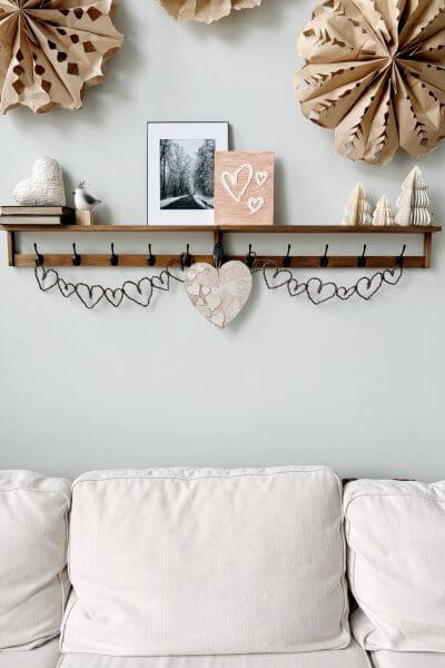 Spackle heart art displayed on shelf above white couch.