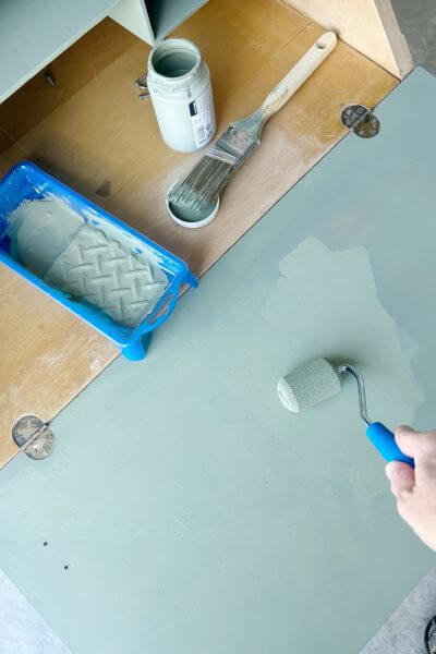Painting the inside portion of the desk with a roller. 