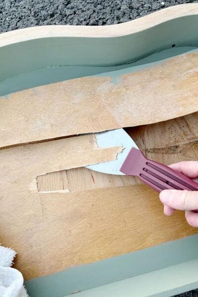 Loosen the veneer with towel and iron and then remove with scraper. 