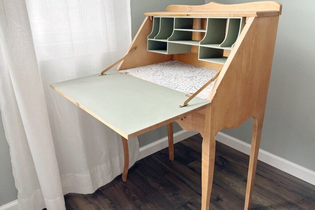 Pic of the completed secretary desk sitting by a window with a white curtain.