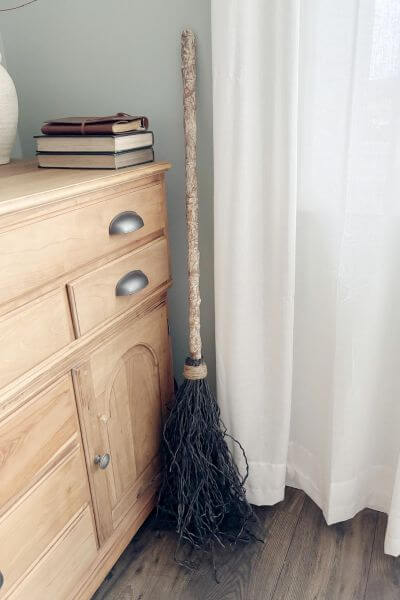 Dollar Tree DIY witch's broom sitting against a wall. 
