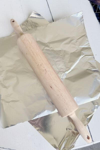 Place a separate piece of tin foil over the clay and roll it out with the rolling pin. 