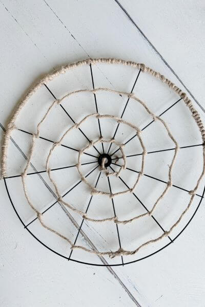 Bicycle wheel wreath form wrapped with jute wire around half of the outer rim. 