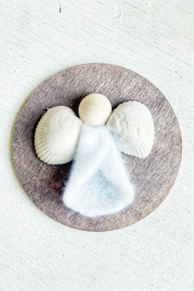 Seashell wings glued to the wood round. 