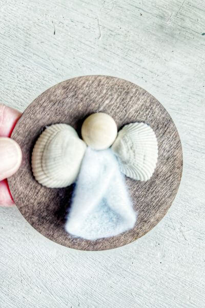 Wood bead head, felt dress and seashell wings glued to the wood round.