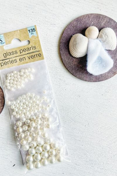 Glass pearl beads package sitting next to angel ornament.