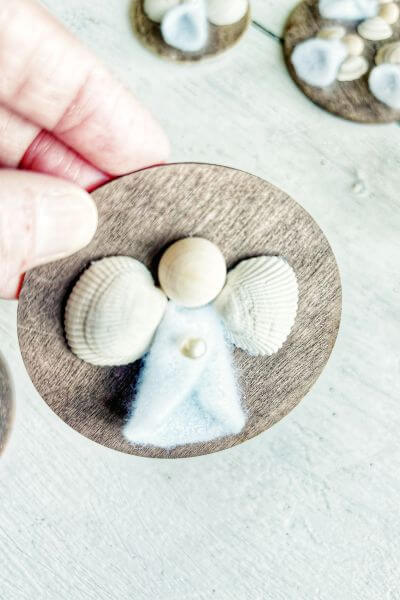 Hot glue a glass pearl in the middle of the angel's dress. 