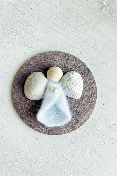 Angel with seashell wings glued onto wood round.