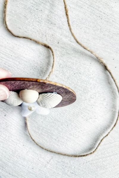 Hot glue around the rim of the wood round starting at the top. 