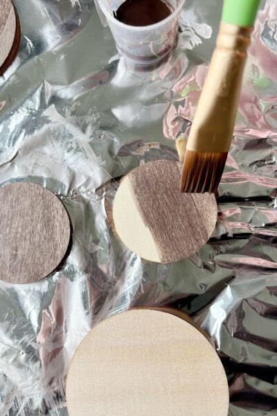 Paint washing the wood rounds with Burnt Umber paint mixed with water. 