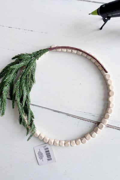 Evergreen pic stem bent in the shape of the wood bead wreath.