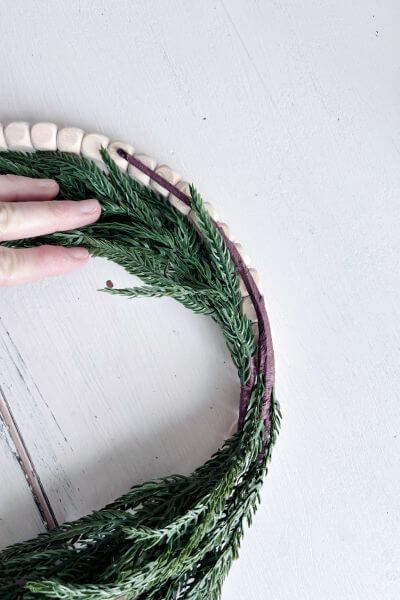Secure the second evergreen pic's stem to the wood bead wreath.