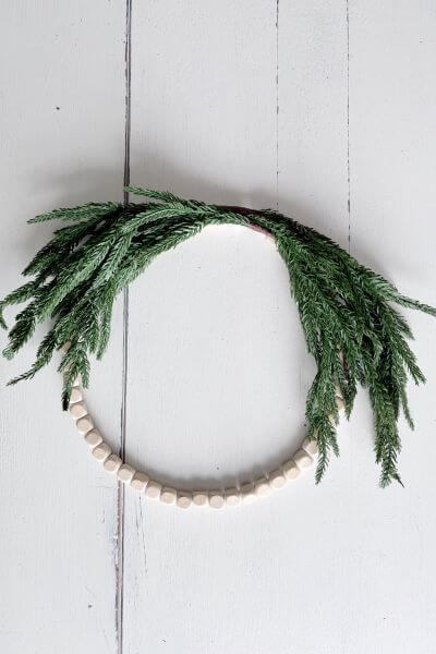 Wood bead wreath with two evergreen pics secured.