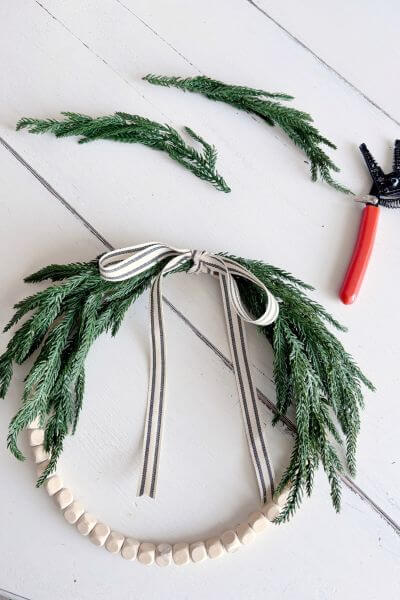 Wood bead evergreen wreath with branches trimmed from each side.