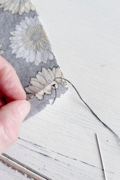 Take the needle through the end of one open side of fabric.