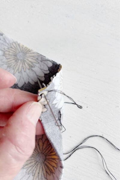 Then on the other side of the fabric bring the thread back through the first stitch hole.