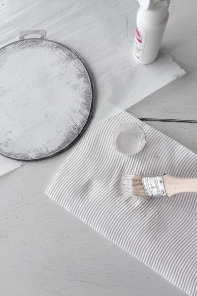 Blot the white paint onto the paper towel before applying it to the wood round.