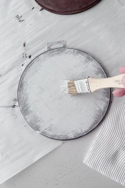 Apply the white paint to the wood round allowing some brown paint to show through.