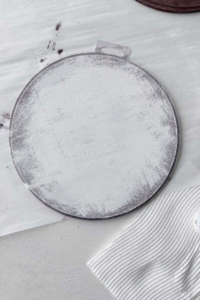 Wood round painted white with brown showing through underneath.