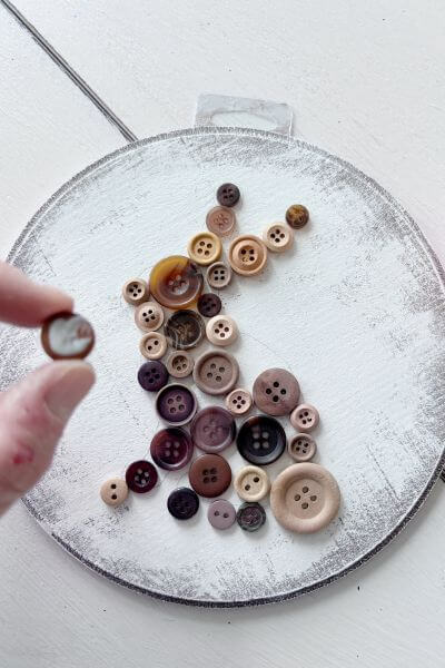 Place a dab of mod podge on the button and then place it in position.