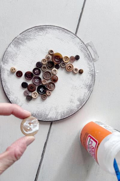 Button with mod podge on it before it's glued to the wood round.