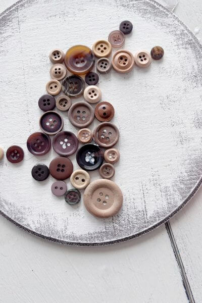 Button applied to the wood round with mod podge in a bunny shape.
